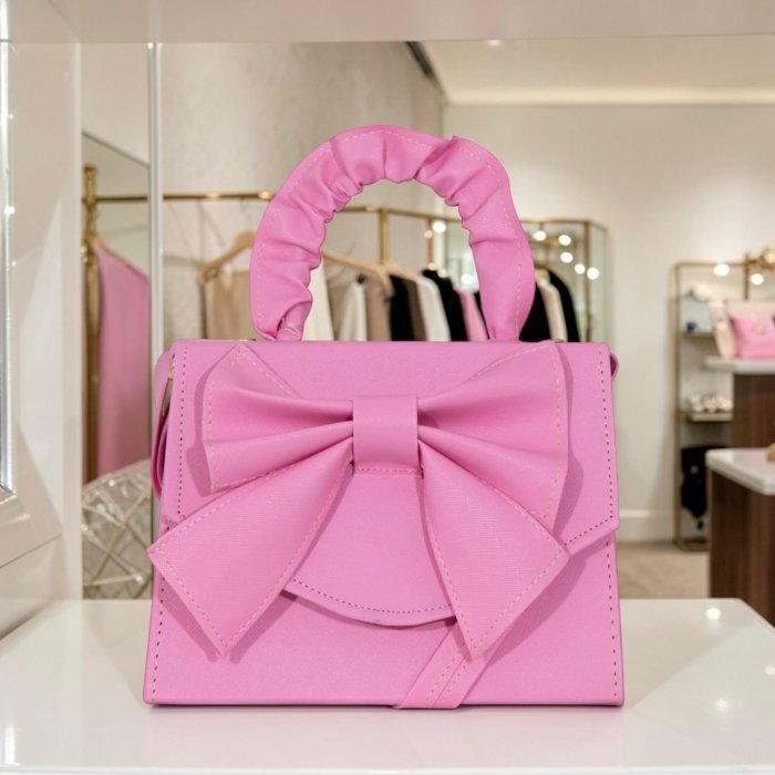 Cross rosa de mano con moño decorativo, elegante y femenina